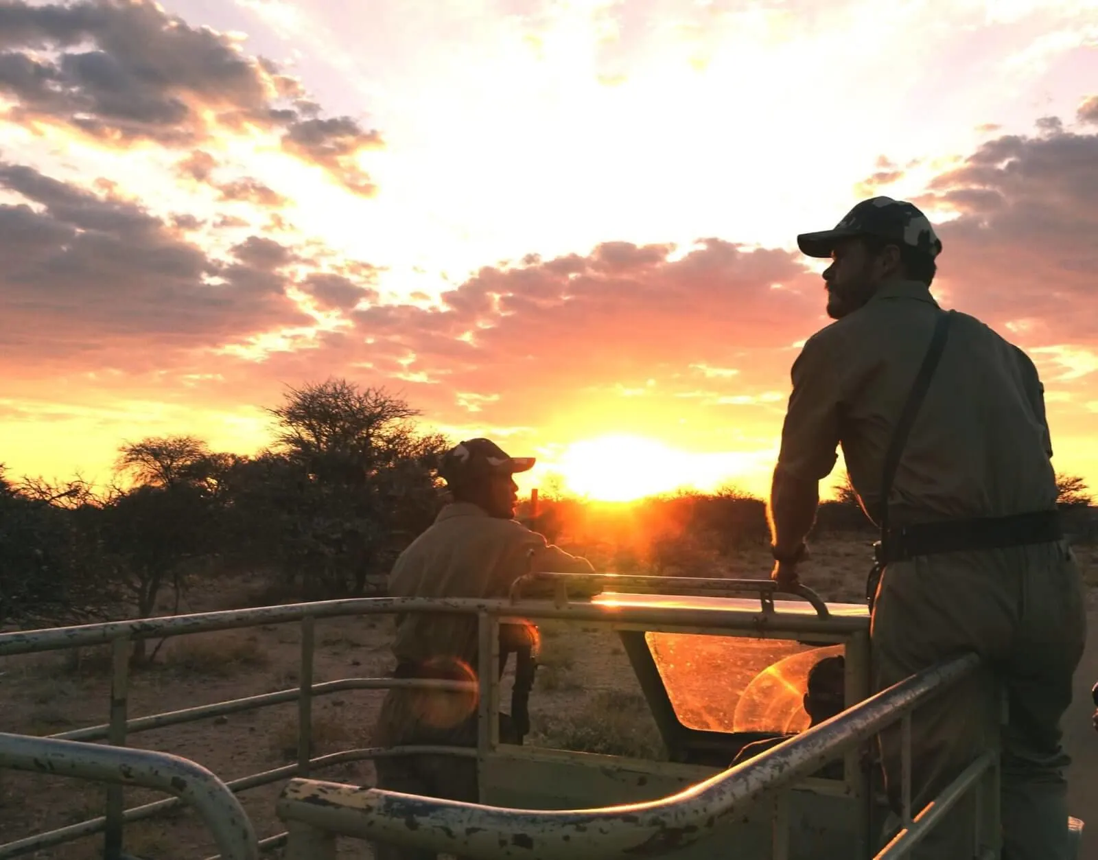 Due ranger a bordo di un mezzo blindato pattugliano la savana africana al tramonto, in missione contro il bracconaggio.