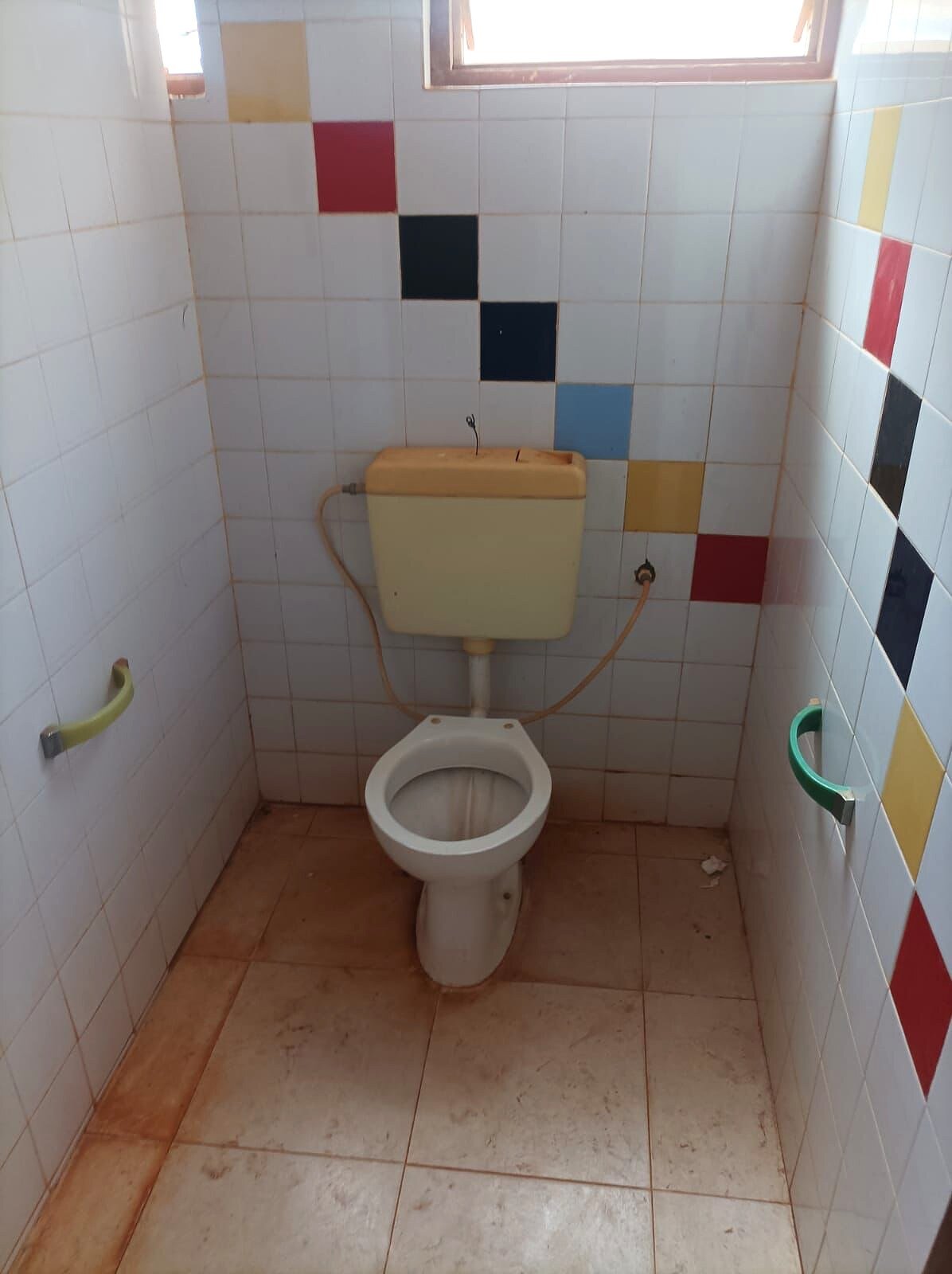 Servizio igienico con sanitari usurati e rivestimento in piastrelle.