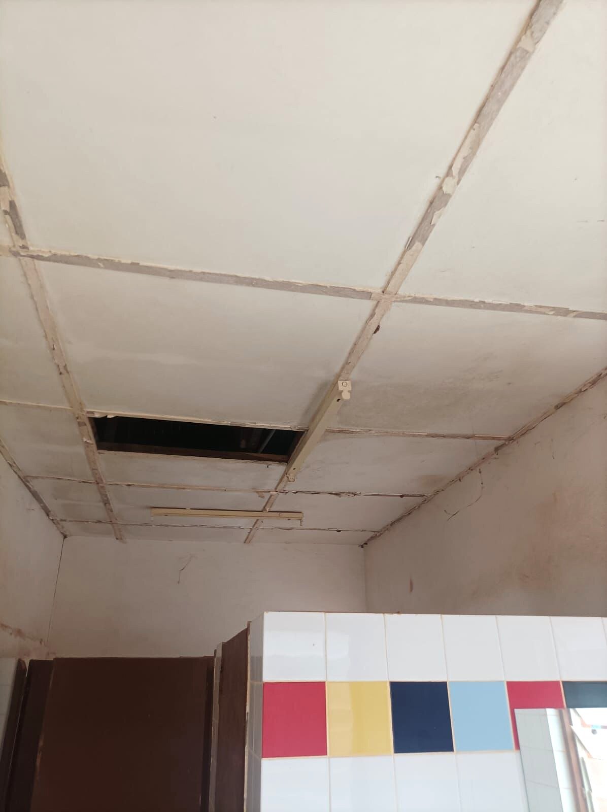 Controsoffitto con un pannello mancante sopra i servizi igienici.