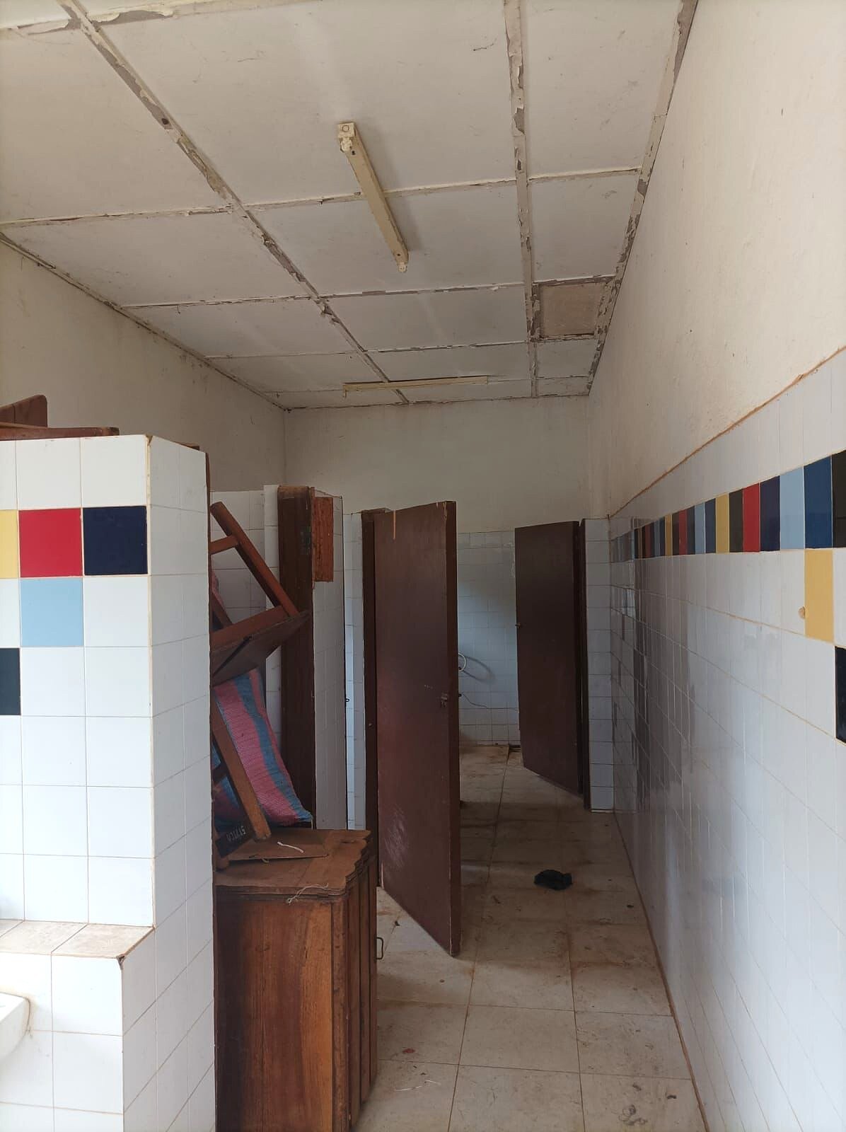 Corridoio dei servizi con controsoffitto deteriorato e porte in legno.